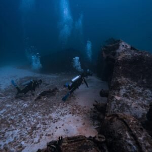 Two scuba divers exploring a shipwreck in the deep ocean waters of Isla Mujeres, Mexico.